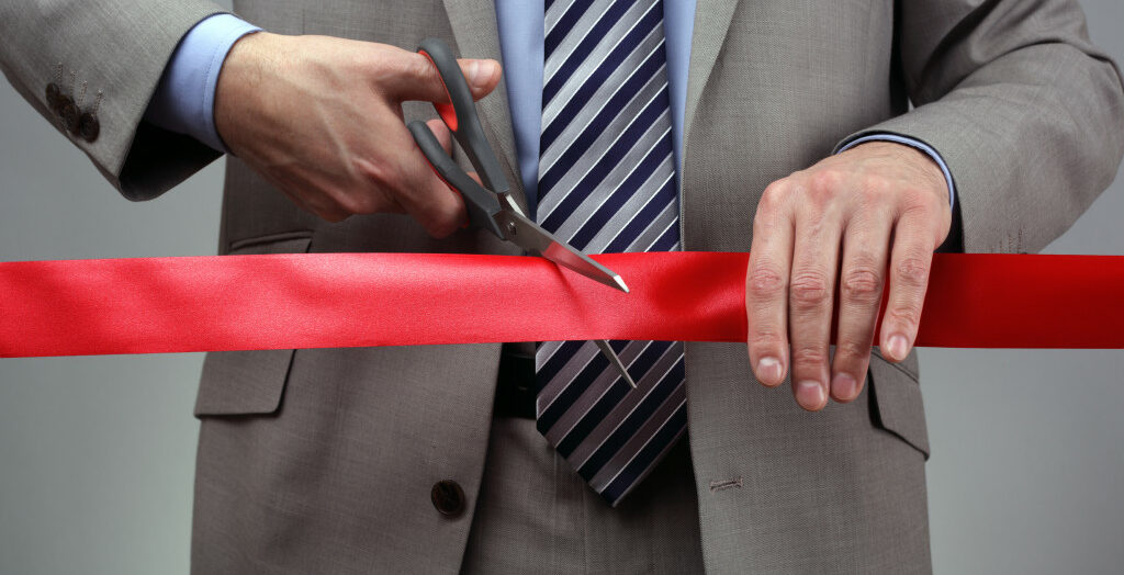 a businessman cutting a red ribbon to open a new business branch