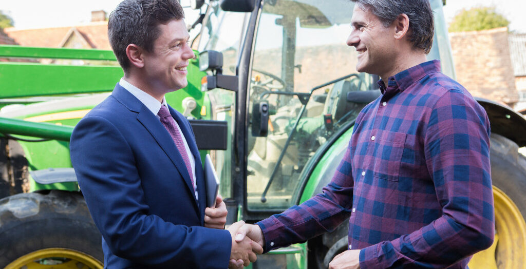 a businessman shaking hands with another businessman in a farm