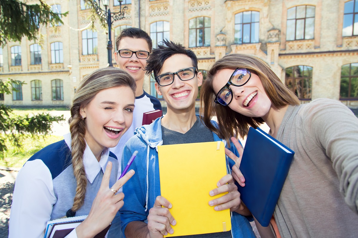 College students smiling after classes in front of a university.