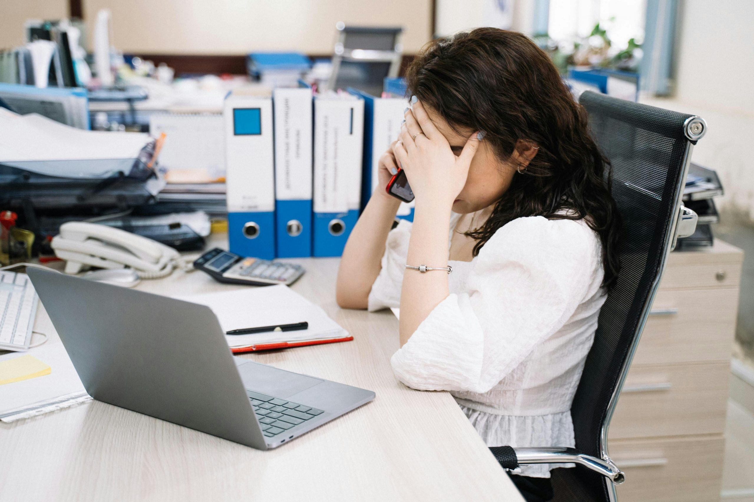 stressed woman making a phone call at her desk