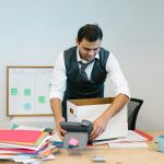 professionally dressed man packing up his desk