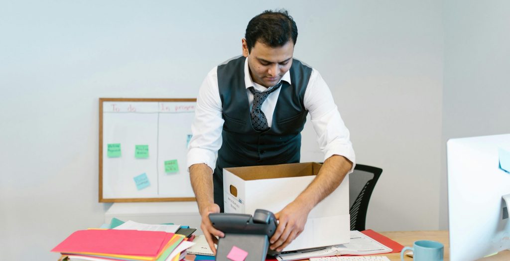 professionally dressed man packing up his desk