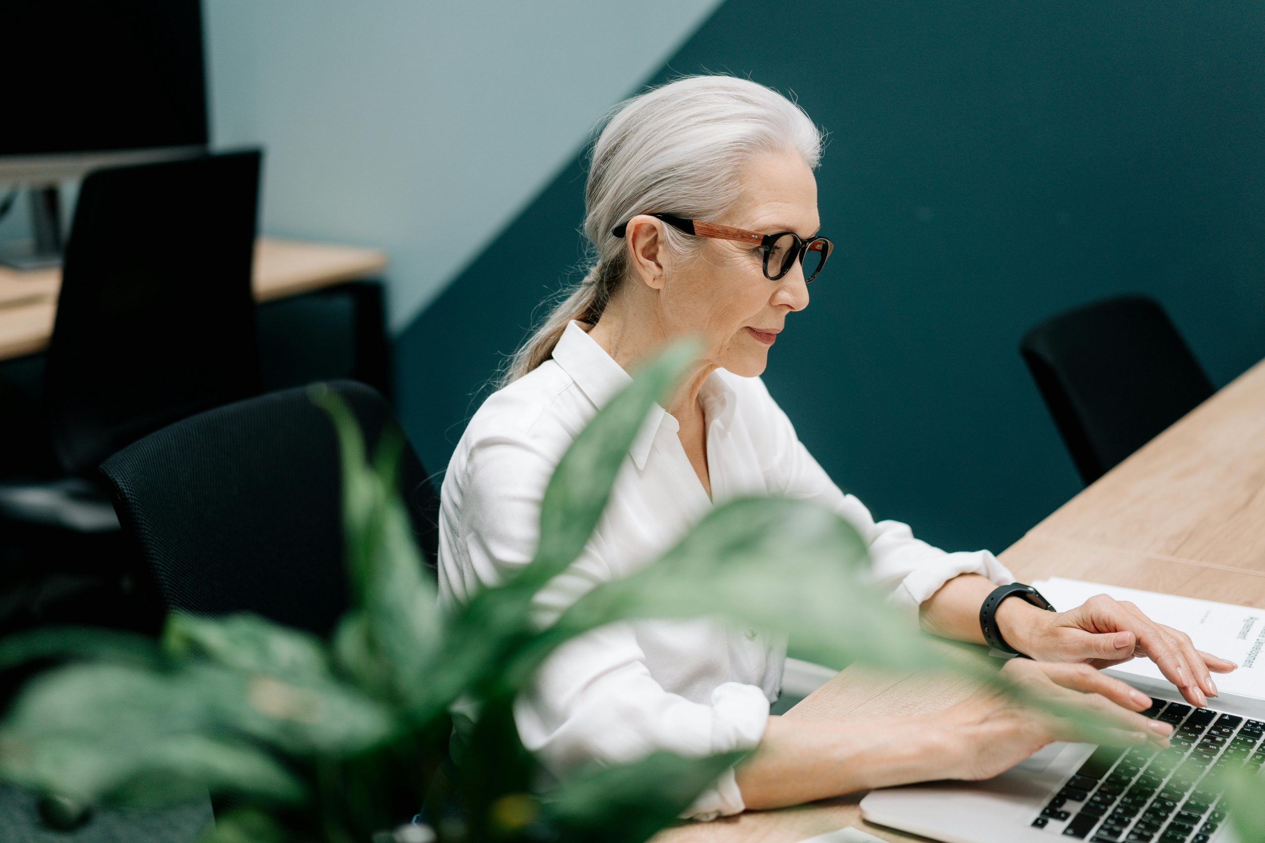 professionally dressed middle-aged woman typing on a laptop