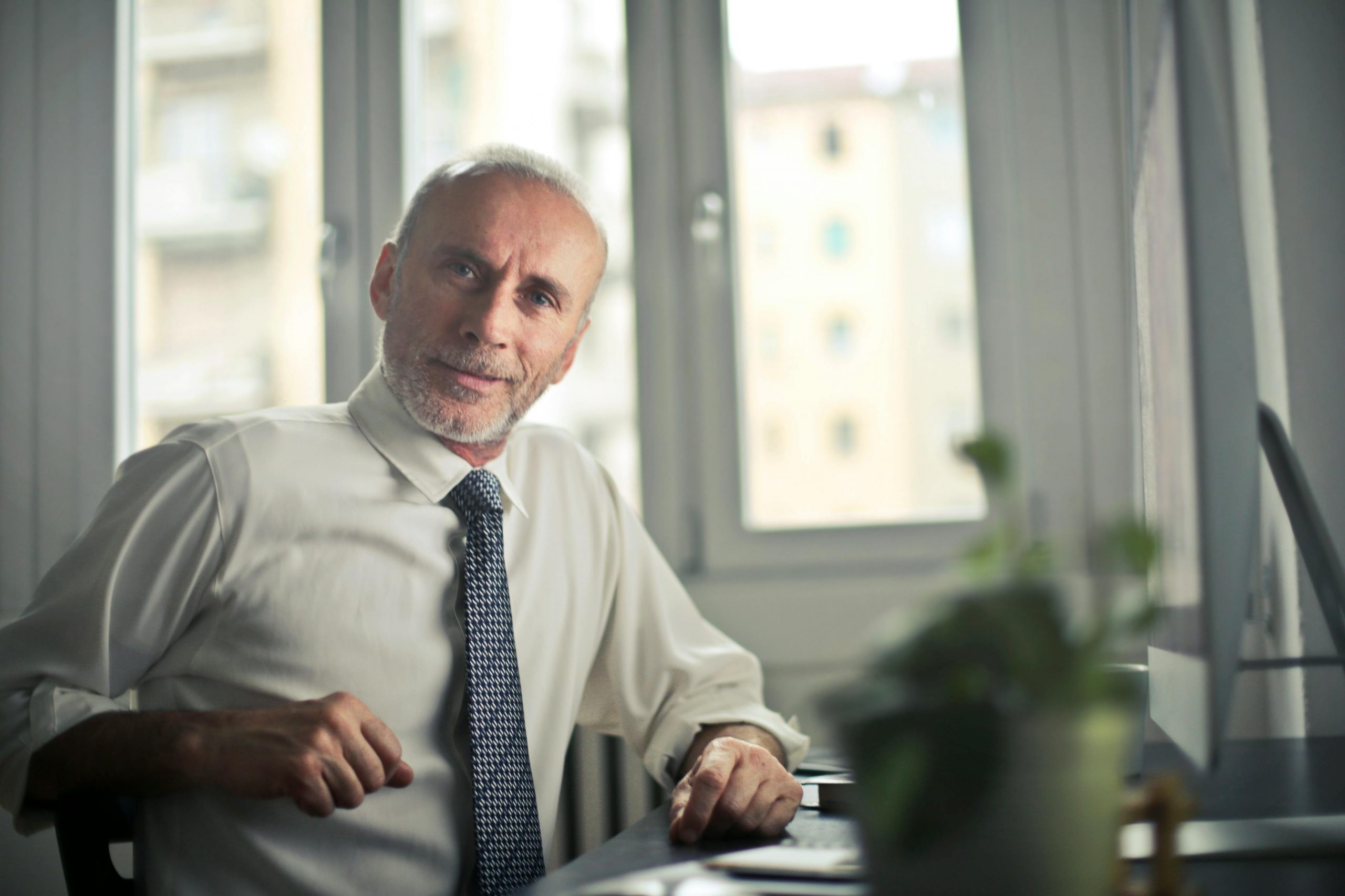 professionally dressed middle-aged man sitting at a desk with a computer
