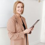 middle-aged woman in a brown blazer holding a tablet